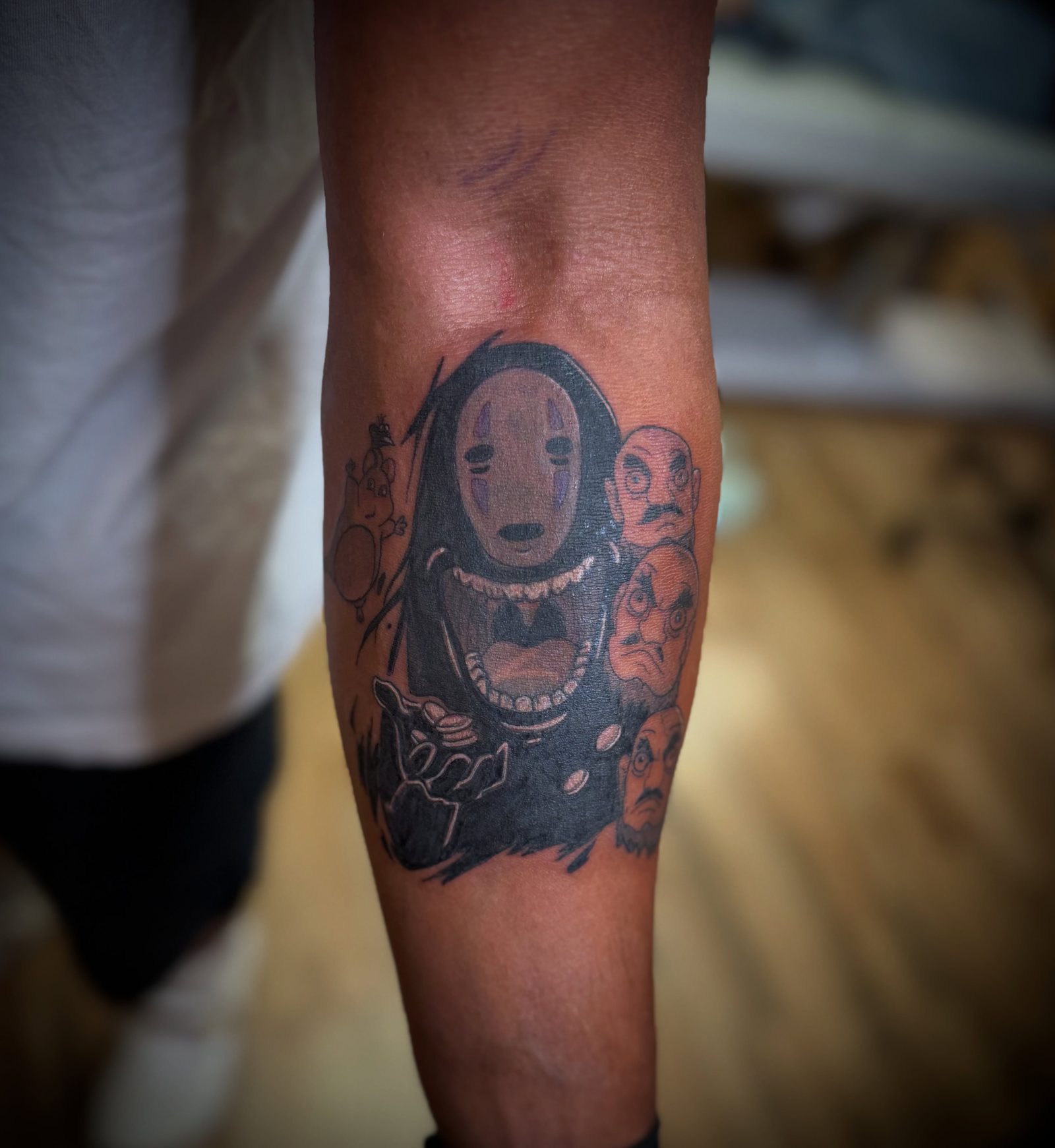 No-Face from Spirited Away in black and grey, tattooed over an older piece